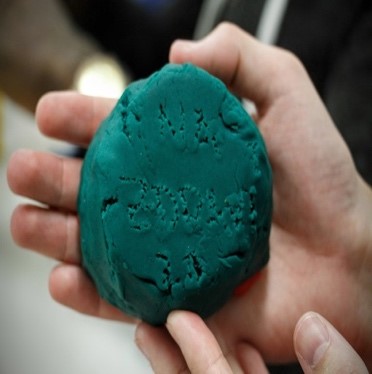 A student holds modeling clay that has inscriptions on it. 